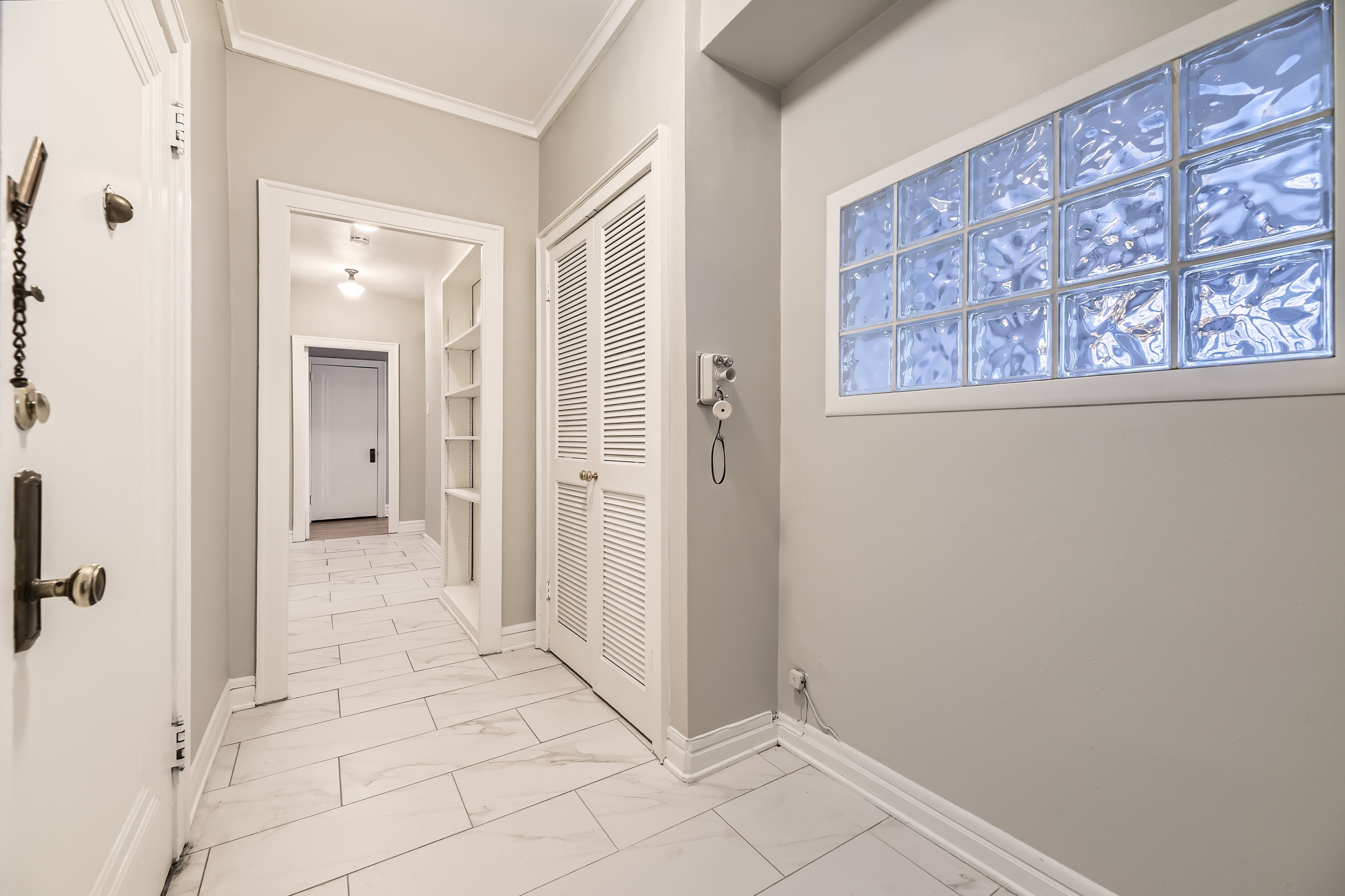 A hallway with a white door and a window with frosted glass.